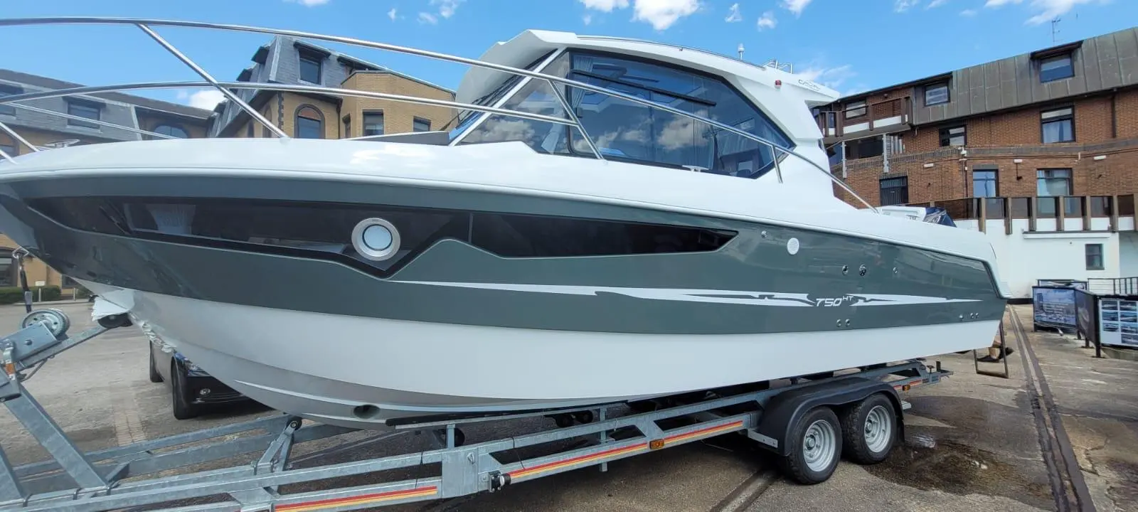 A sleek T50 HT boat on a trailer, with modern design features, parked in a location with buildings and blue sky in the background.